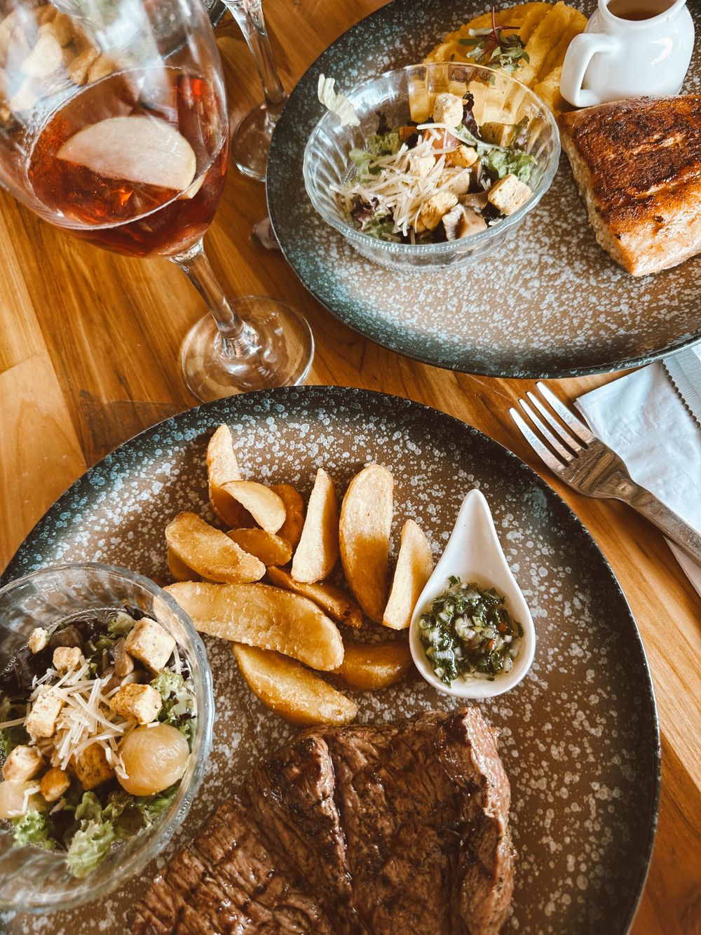 Steak hasábburgonyával, salátával és vörösborral fa asztalon